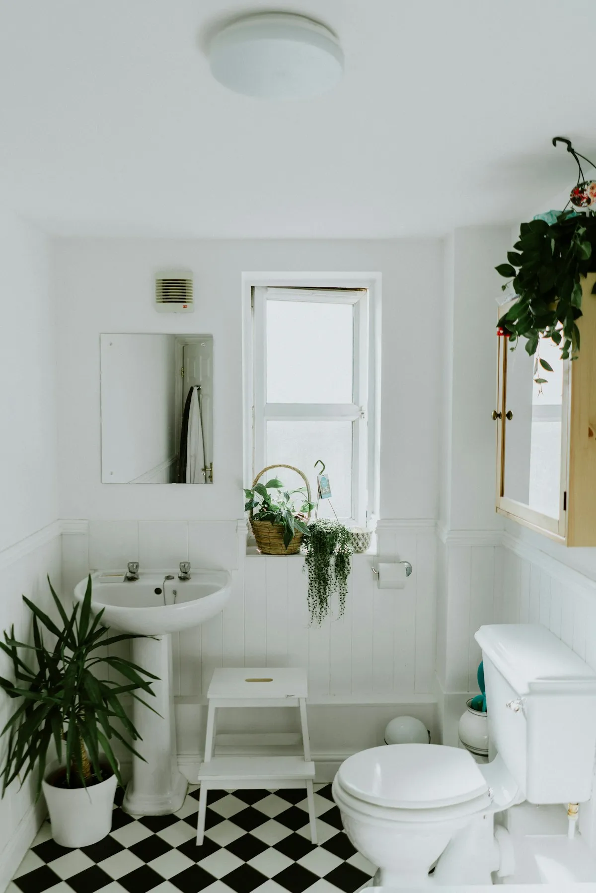 A bright, clean white bathroom with a toilet and checkered floor tiles