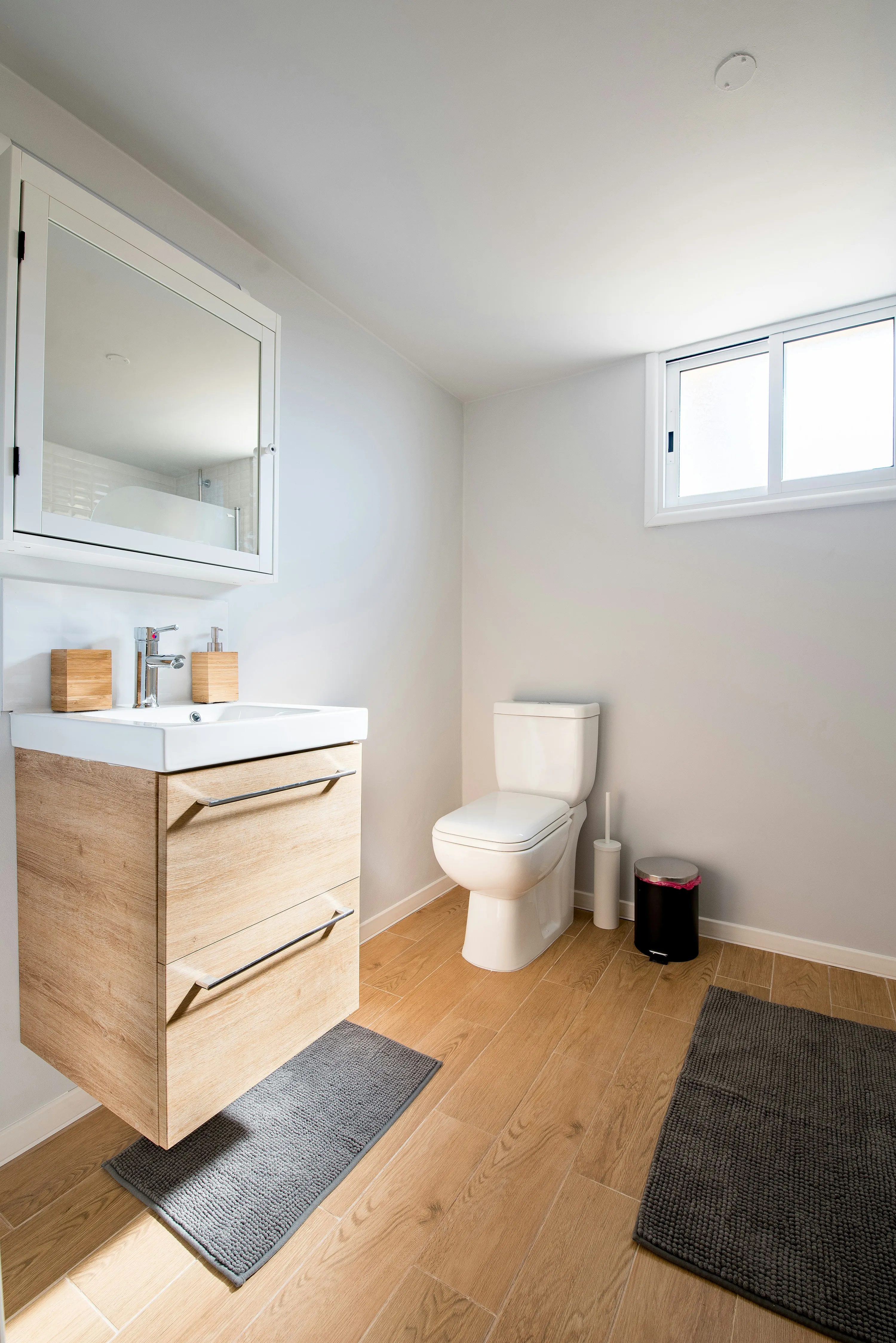 A clean, modern white bathroom with a toilet and vanity